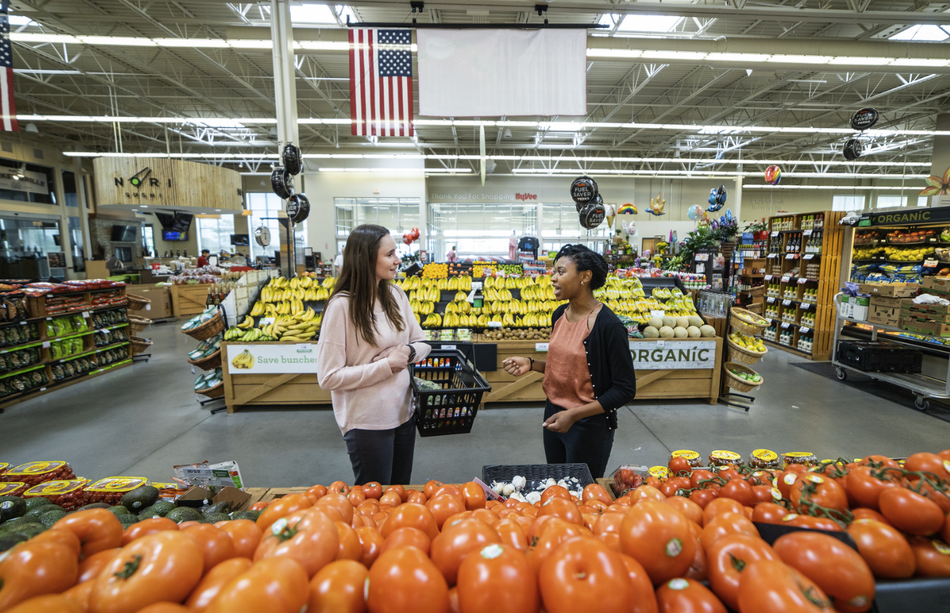 Two women talking in a grocery store produce aisle. One dietitian, one client.